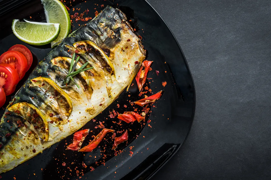 Grilled mackerel with lime on a black plate